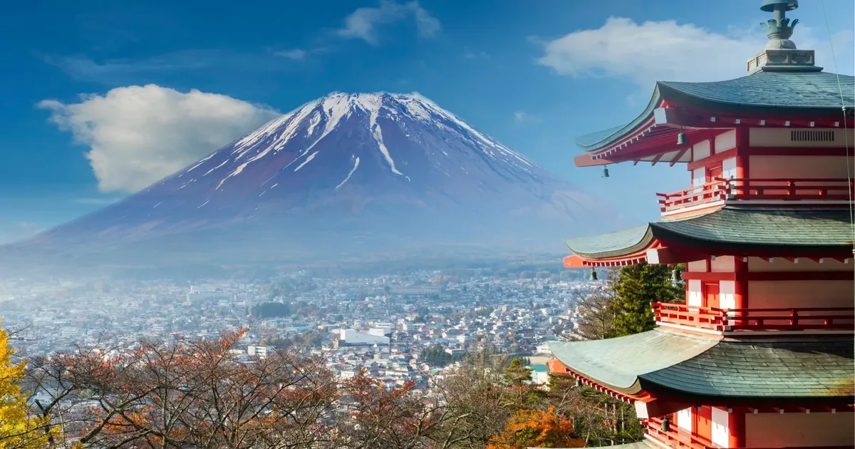 The red five-storey Chureito Pagoda above Fujiyoshida in late autumn, with Mount Fuji rising behind the town