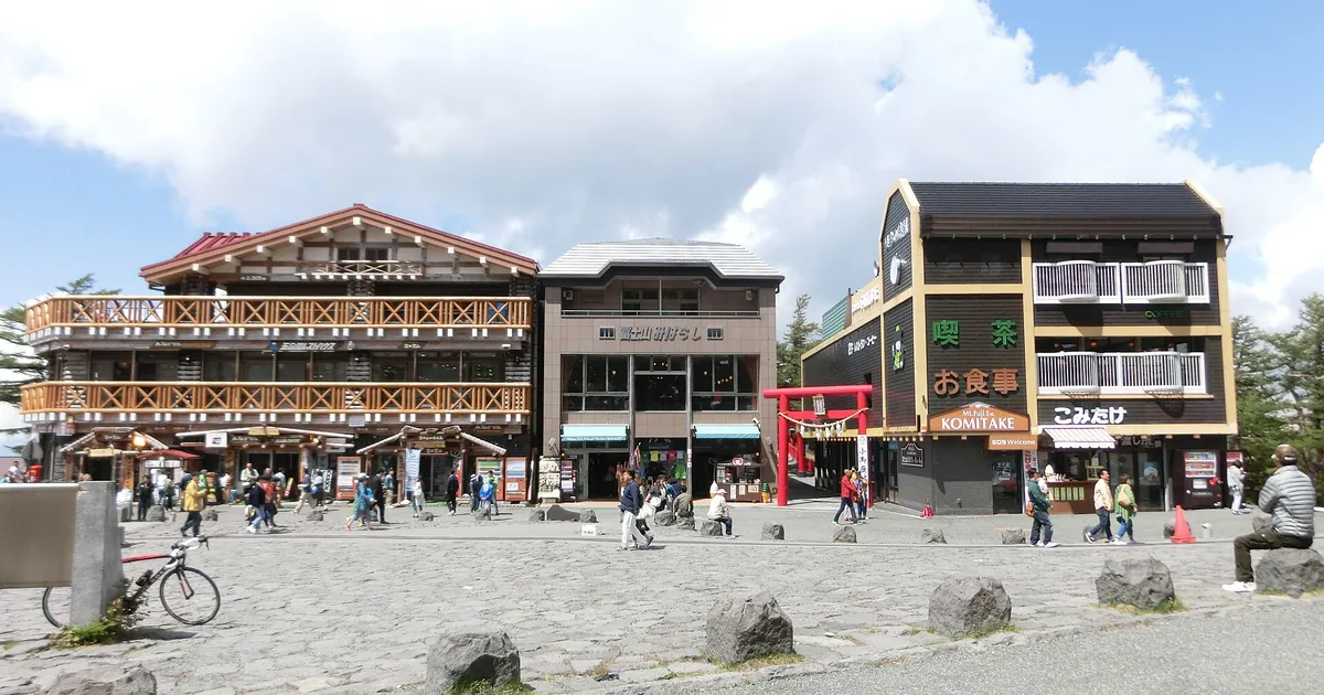 The plaza at the Fuji Subaru Line 5th Station, with the log-built Gogoen Rest House, the Fujisan Miharashi building and the red torii of Komitake Shrine beside the Komitake shop
