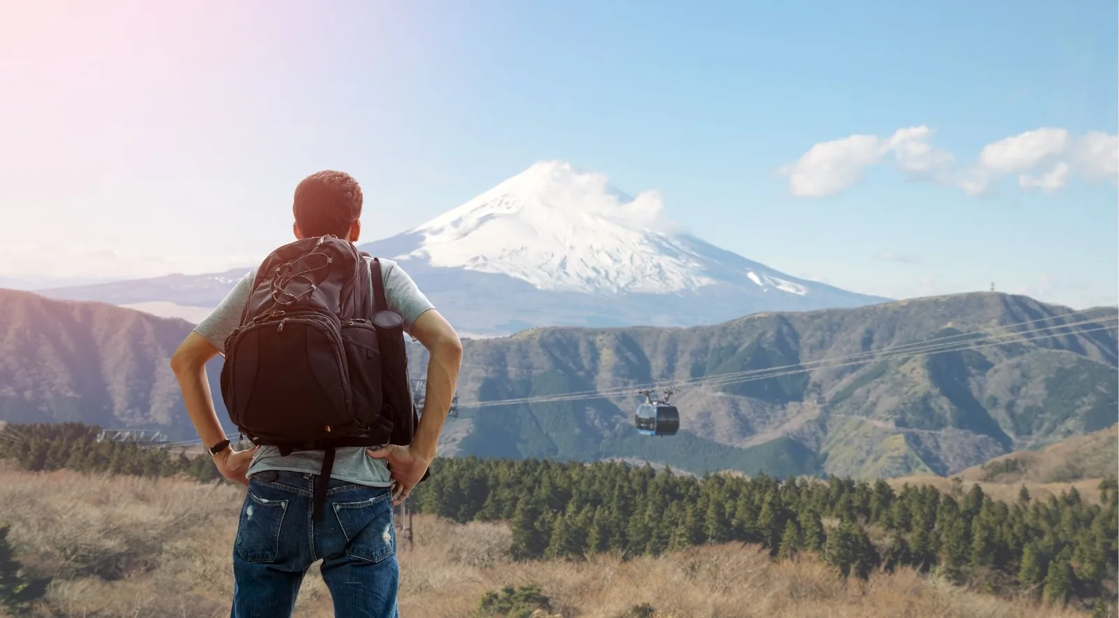 A traveller watching Mount Fuji as a Hakone Ropeway gondola crosses the valley