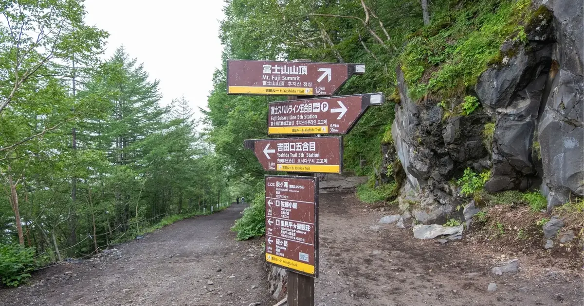 Multilingual trail signposts at the Fuji Subaru Line 5th Station pointing to the Mount Fuji summit