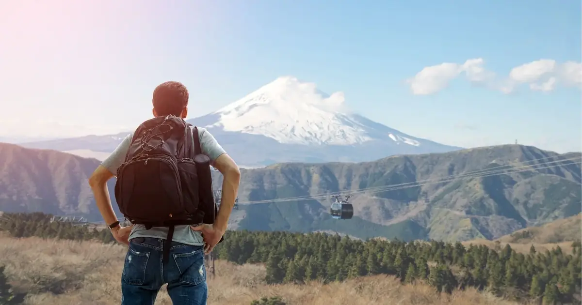 A Hakone Ropeway gondola crossing the valley with Mount Fuji beyond, on a combined Fuji and Hakone day